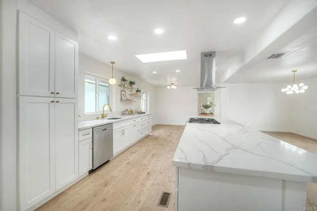 a large white kitchen with kitchen island a sink stainless steel appliances and cabinets