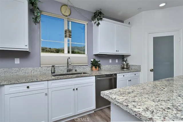 a kitchen with stainless steel appliances granite countertop sink stove refrigerator and wooden floor