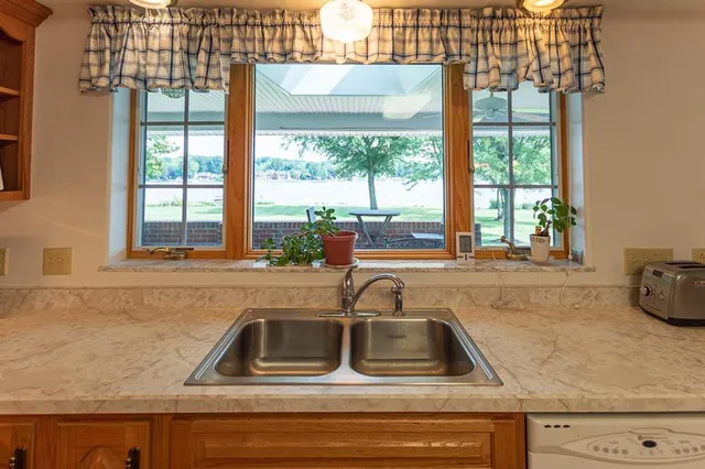 a kitchen sink with granite countertop a large window
