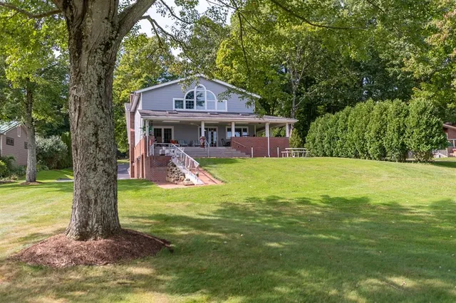 a view of a house with a yard balcony and a tree