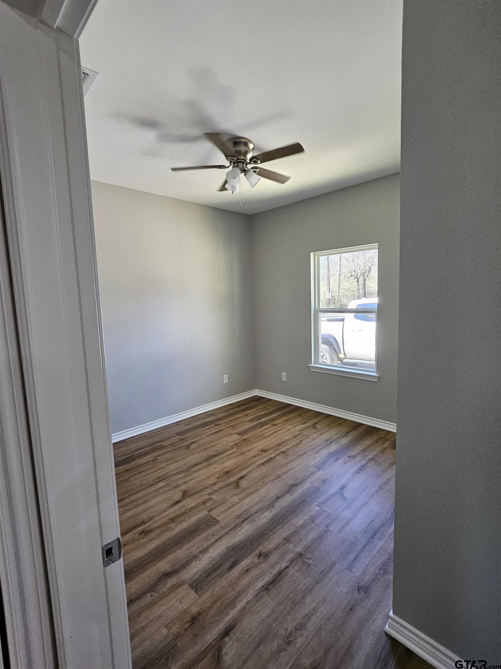 100 Cook Street, Unit 3 Arp, TX 75750 - Photo 5 of 7 an empty room with wooden floor fan and windows