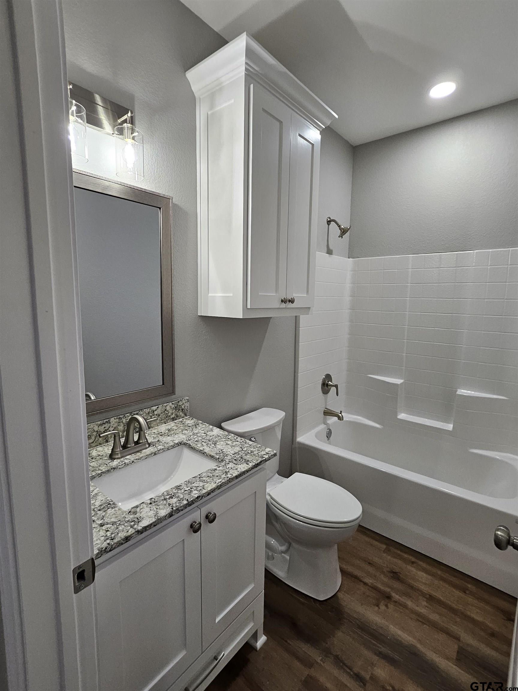 100 Cook Street, Unit 3 Arp, TX 75750 - Photo 7 of 7 a bathroom with a granite countertop sink a toilet a mirror and bathtub