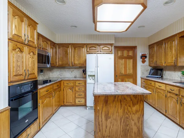 a kitchen with stainless steel appliances granite countertop wooden cabinets a stove a sink and a large window