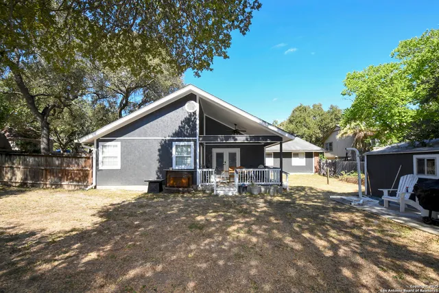 a view of a backyard with wooden fence and a large tree