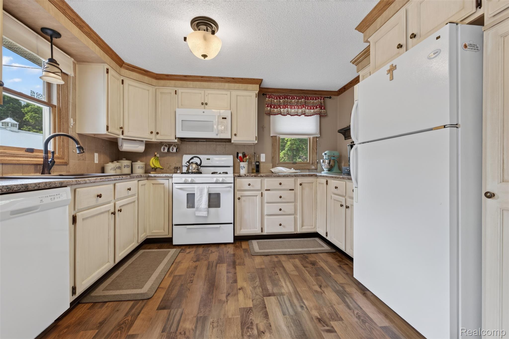 5977 Anglers Road Ortonville, MI 48462 - Photo 10 of 63 Kitchen featuring wood-finish flooring, cream cabinetry, dark countertops, built-in microwave, and a white appliance suite