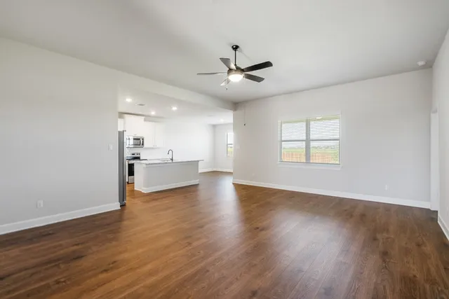 a kitchen with stainless steel appliances granite countertop a refrigerator a sink dishwasher a stove and white countertops with wooden floor