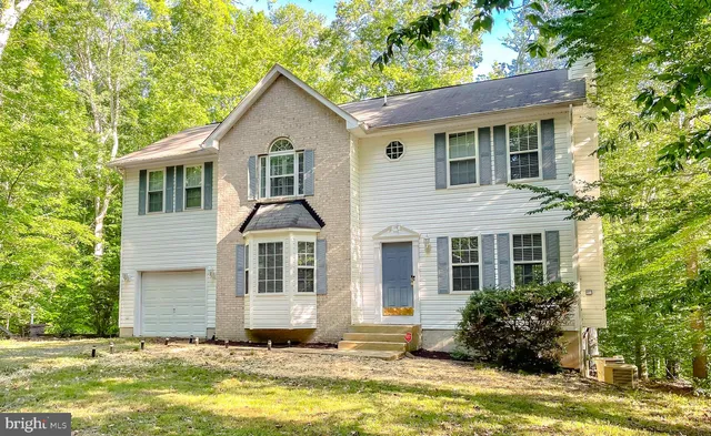 a front view of a house with a garden and trees