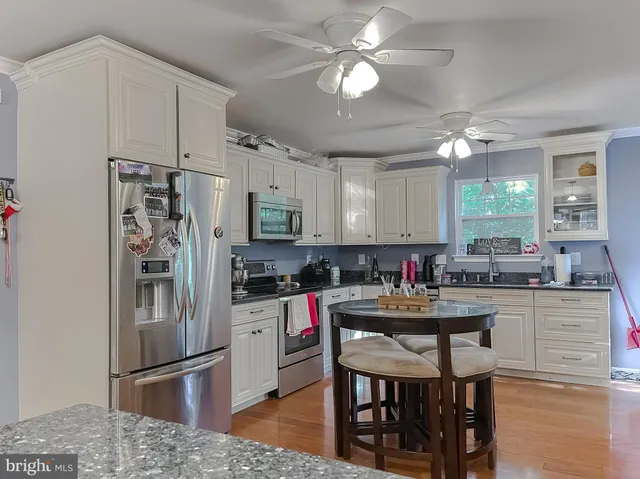 a kitchen with stainless steel appliances granite countertop a dining table chairs refrigerator and cabinets