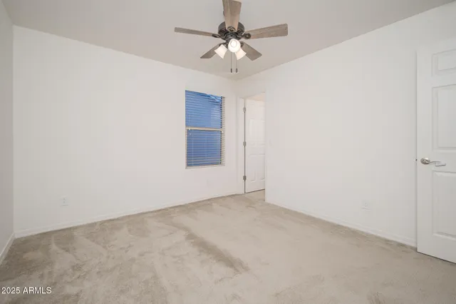 an empty room with a chandelier fan and windows