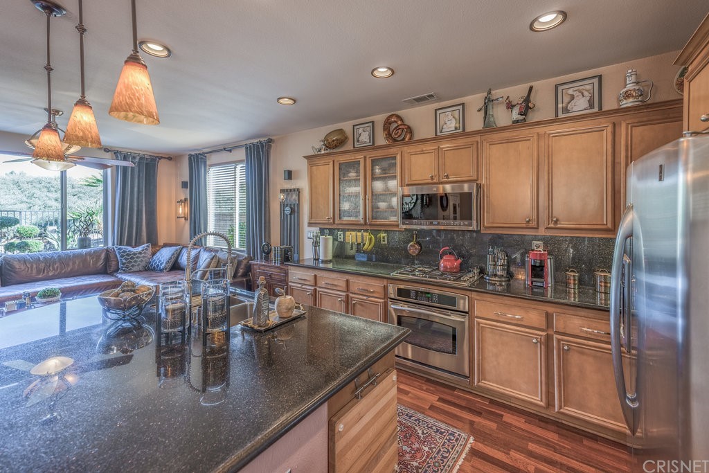 29021 Mirada Circulo Valencia, CA 91354 - Photo 13 of 57 a kitchen with stainless steel appliances granite countertop a refrigerator a sink dishwasher a stove and a dining table with wooden floor