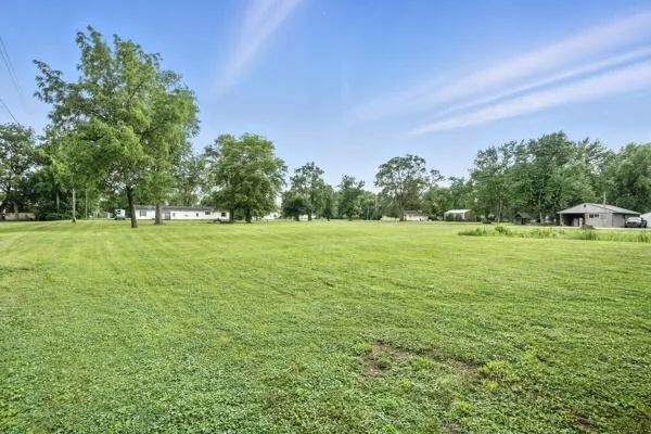 a view of a green field with trees in the background