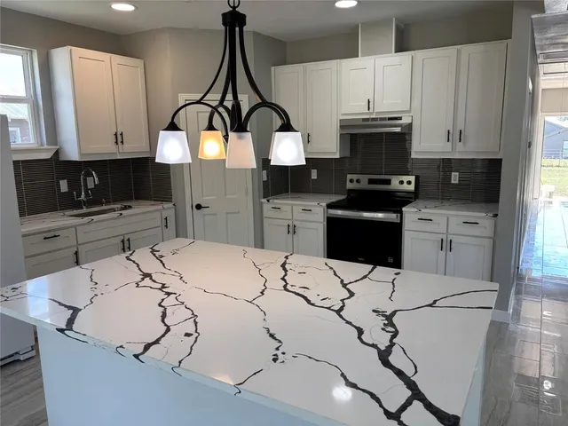 a kitchen with granite countertop a sink stainless steel appliances and white cabinets