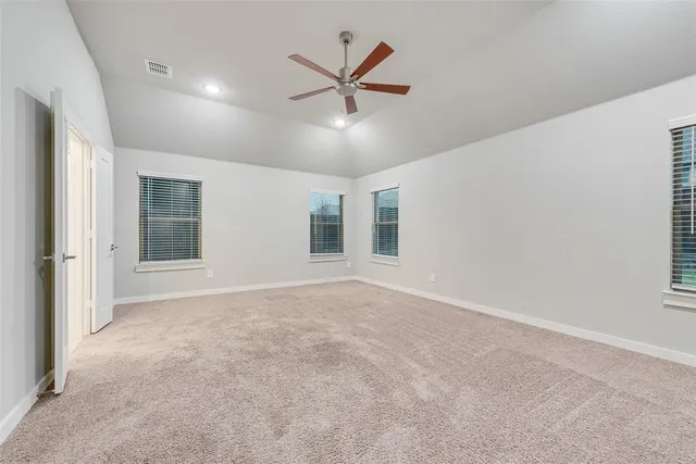 an empty room with ceiling fan and window