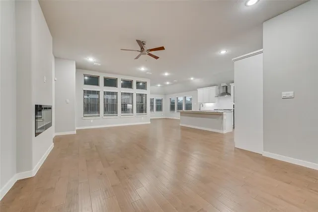 a view of an empty room with a window and kitchen view