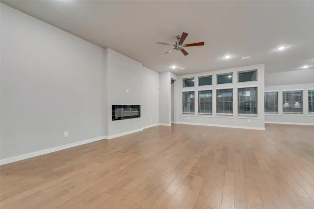 a view of an empty room with a window and a kitchen