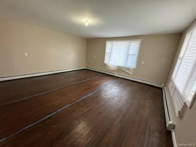 an empty room with wooden floor and windows with curtains
