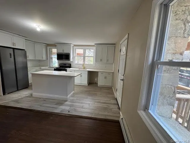 a view of a kitchen with a sink refrigerator and wooden floor