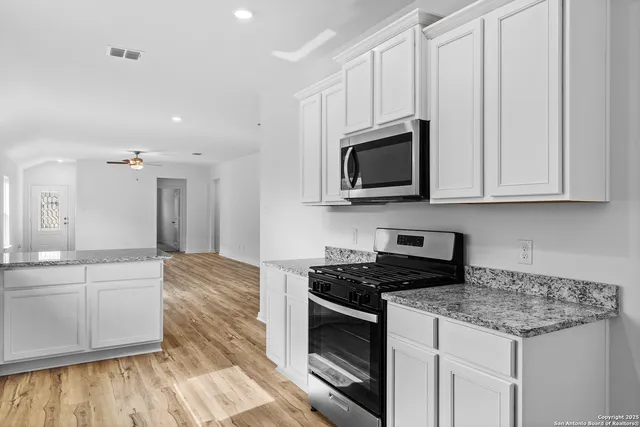 a kitchen with stainless steel appliances granite countertop a stove a sink and a microwave