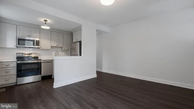 a kitchen with wooden floors and white stainless steel appliances