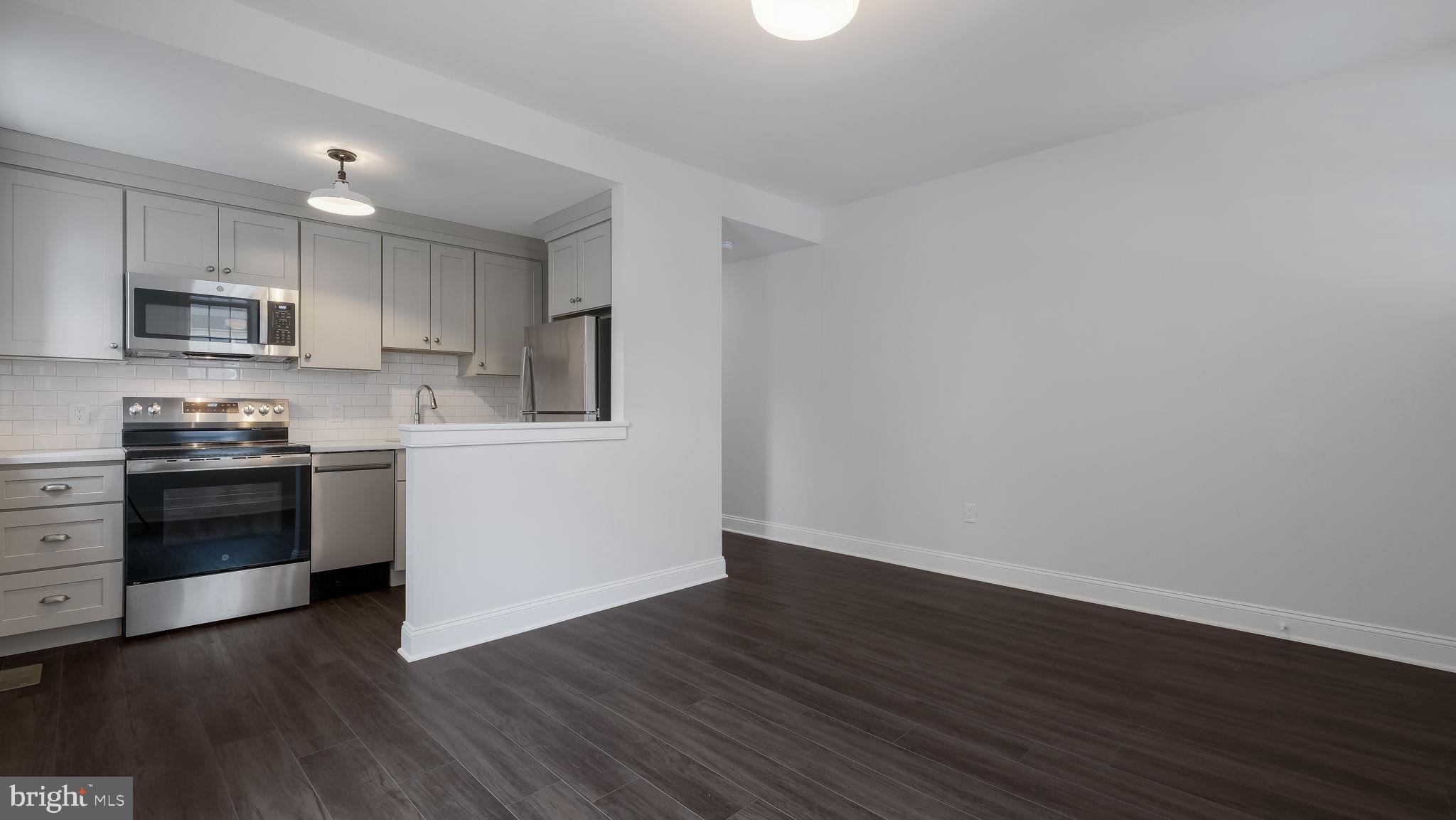 115 Harvey Avenue, Unit 1171 Doylestown, PA 18901 - Photo 9 of 26 a kitchen with wooden floors and white stainless steel appliances