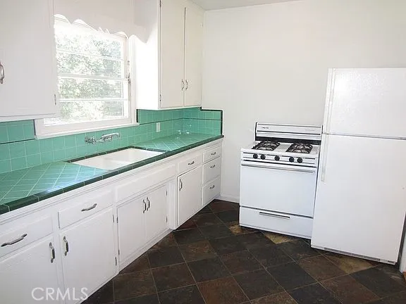 a kitchen with granite countertop white cabinets and white appliances