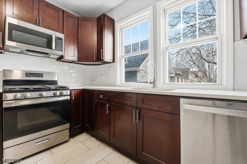76 Riggs Place, Unit 2 West Orange, NJ 07052 - Photo 5 of 24 a kitchen with granite countertop wooden cabinets stainless steel appliances and a window