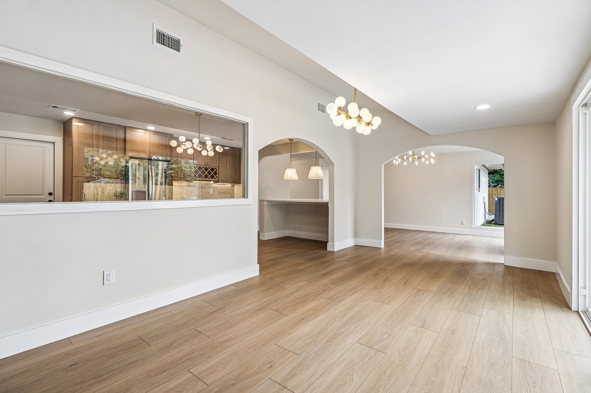 11809 Charing Cross Road Austin, TX 78759 - Photo 11 of 34 A luminous living space features vaulted ceilings, natural wood-look flooring, and graceful arched doorways.