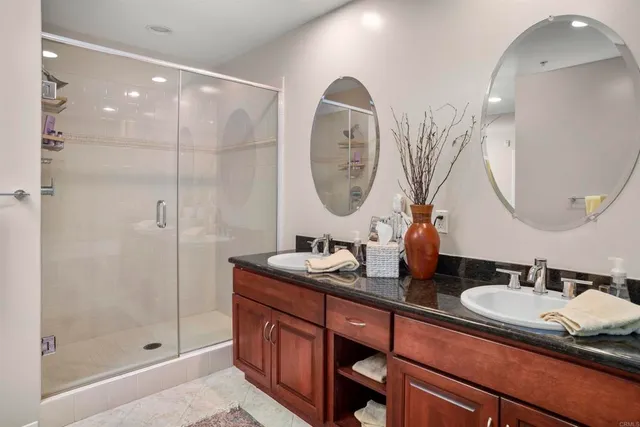 a bathroom with a double vanity sink mirror and shower