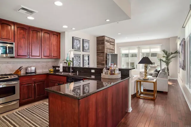 a kitchen with stainless steel appliances granite countertop a stove a sink dishwasher and cabinets with wooden floor