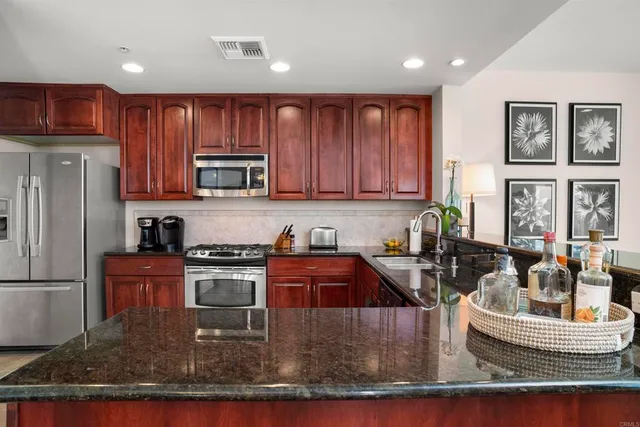 a kitchen with stainless steel appliances granite countertop a stove a refrigerator a sink a microwave and living room
