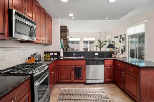 a kitchen with stainless steel appliances granite countertop a stove a sink and a microwave