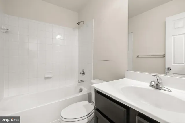 a bathroom with a bathtub shower sink vanity mirror and toilet
