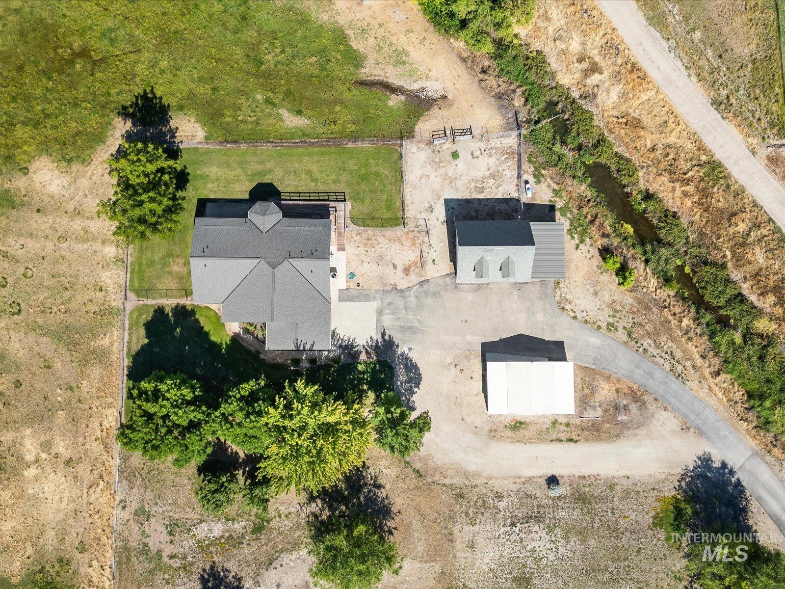 3540 Wills Road Emmett, ID 83617 - Photo 36 of 36 Aerial property overview featuring a main residence with a multi-gabled roof, an auxiliary structure with gabled dormers, a separate white outbuilding, and a paved driveway