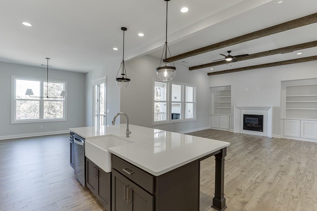 446 Thunder Road Buford, GA 30518 - Photo 14 of 79 a kitchen with a stove center island a sink dishwasher and a fireplace with wooden floor