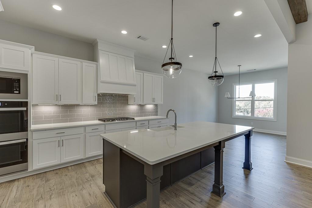 446 Thunder Road Buford, GA 30518 - Photo 9 of 79 a kitchen with a stove a sink dishwasher a dining table and chairs with wooden floor