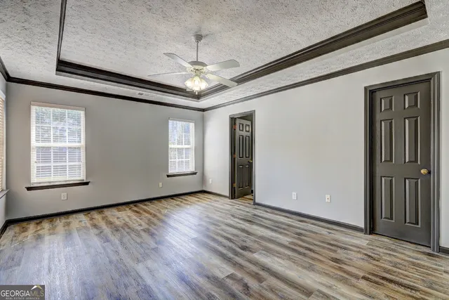 an empty room with wooden floor chandelier and windows