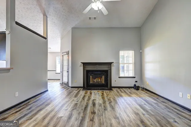 an empty room with wooden floor a fireplace and windows