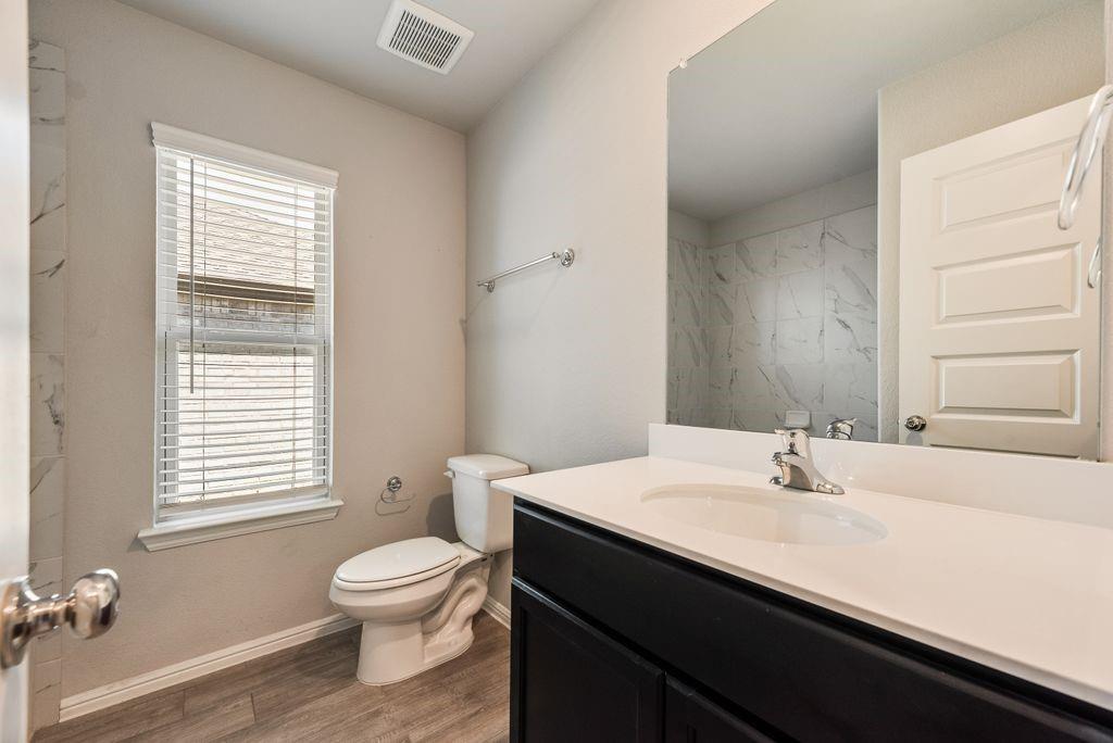 14216 Aberavon Drive Pilot Point, TX 76258 - Photo 17 of 19 Bathroom featuring wood-finish flooring, a white vanity with an integrated sink, chrome faucet, and a large wall-mounted mirror