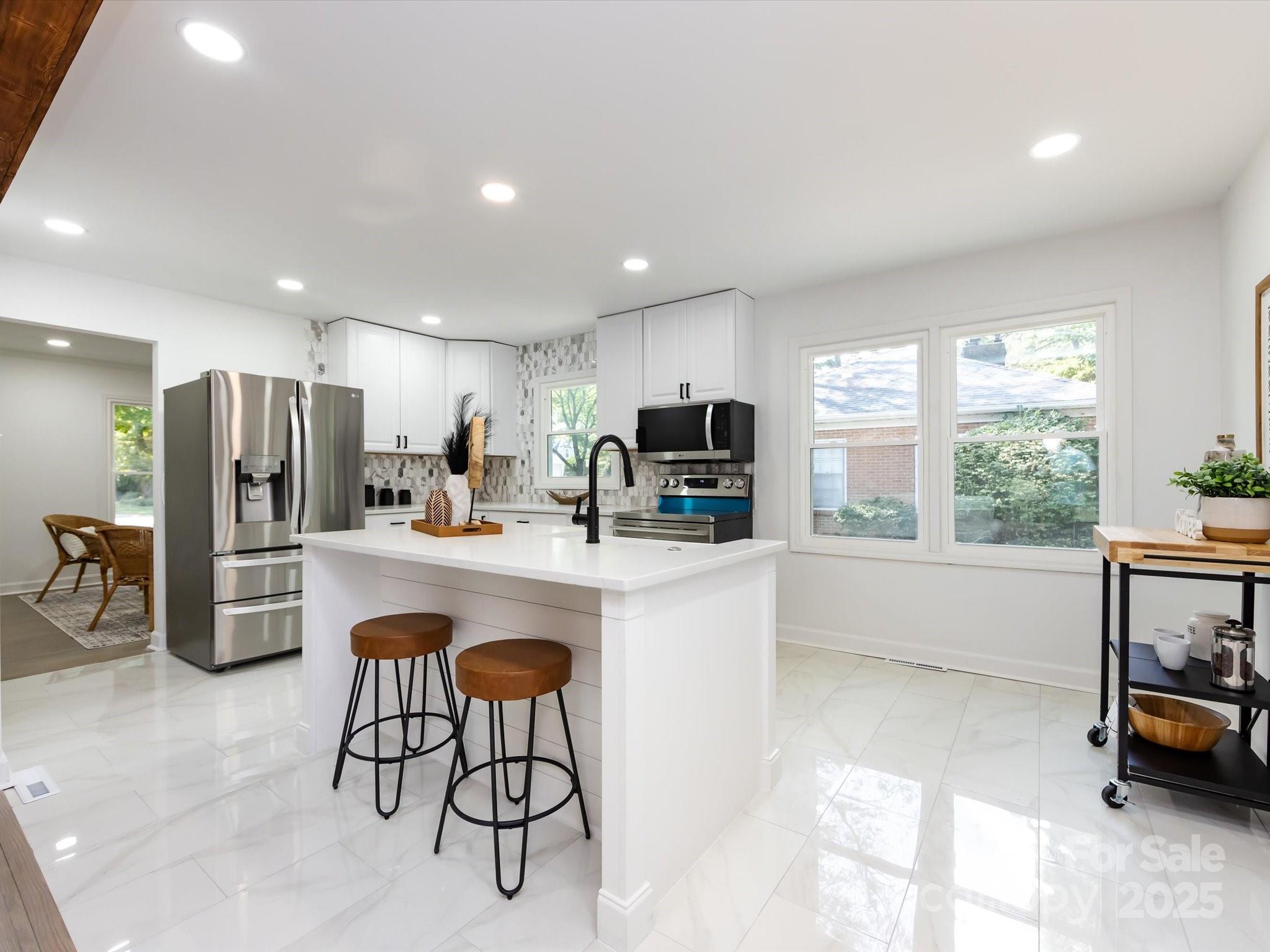 6017 Brace Road Charlotte, NC 28211 - Photo 18 of 47 a kitchen with stainless steel appliances a refrigerator a sink a stove a dining table and chairs with wooden floor