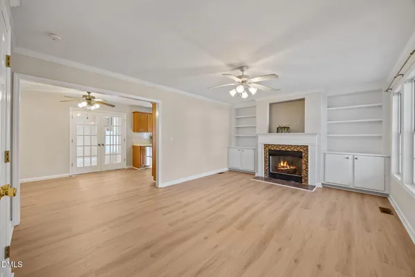a view of an empty room with wooden floor fireplace and a window