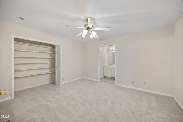 an empty room with chandelier fan and windows