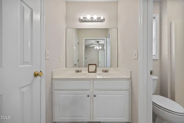 a view of an empty room with chandelier fan and windows