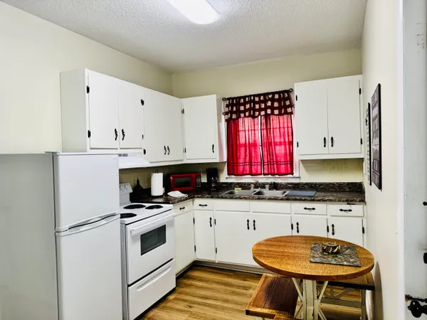a kitchen with granite countertop a sink a stove and cabinets