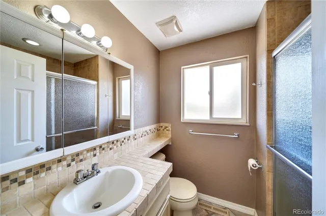 a bathroom with a sink a toilet and shower