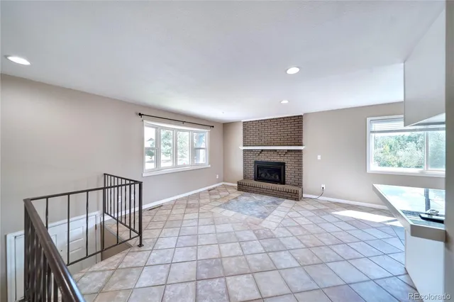 an empty room with windows and fireplace