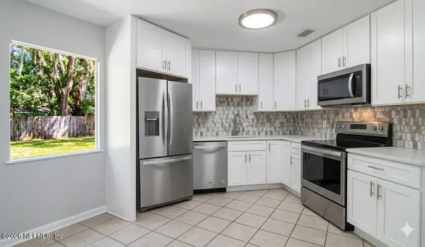 a kitchen with white cabinets stainless steel appliances and a window