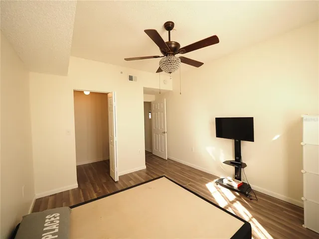 a view of a room with a ceiling fan and wooden floor
