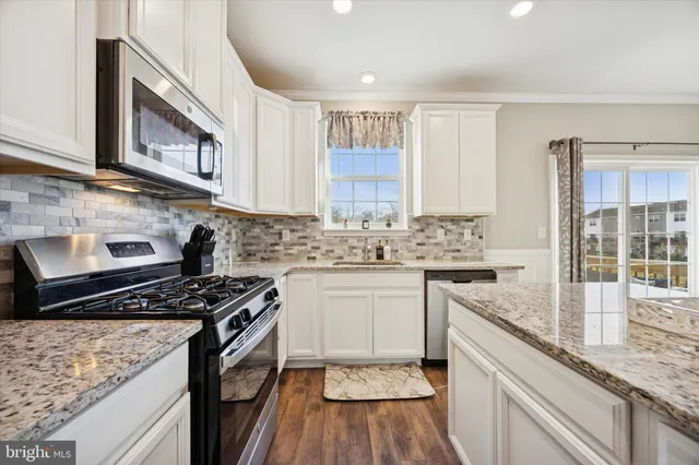 a kitchen with granite countertop a stove sink and cabinets