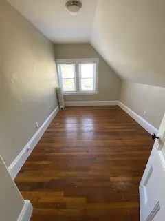 a view of an empty room with wooden floor and window