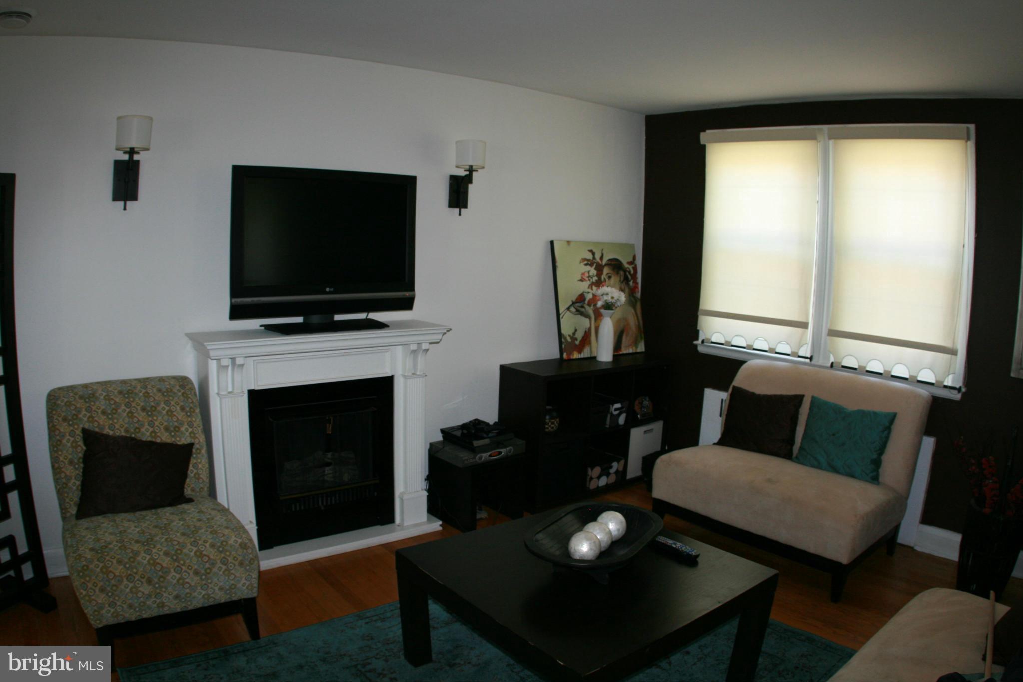 429 Academy Road Catonsville, MD 21228 - Photo 3 of 26 a living room with furniture a flat screen tv and a fireplace